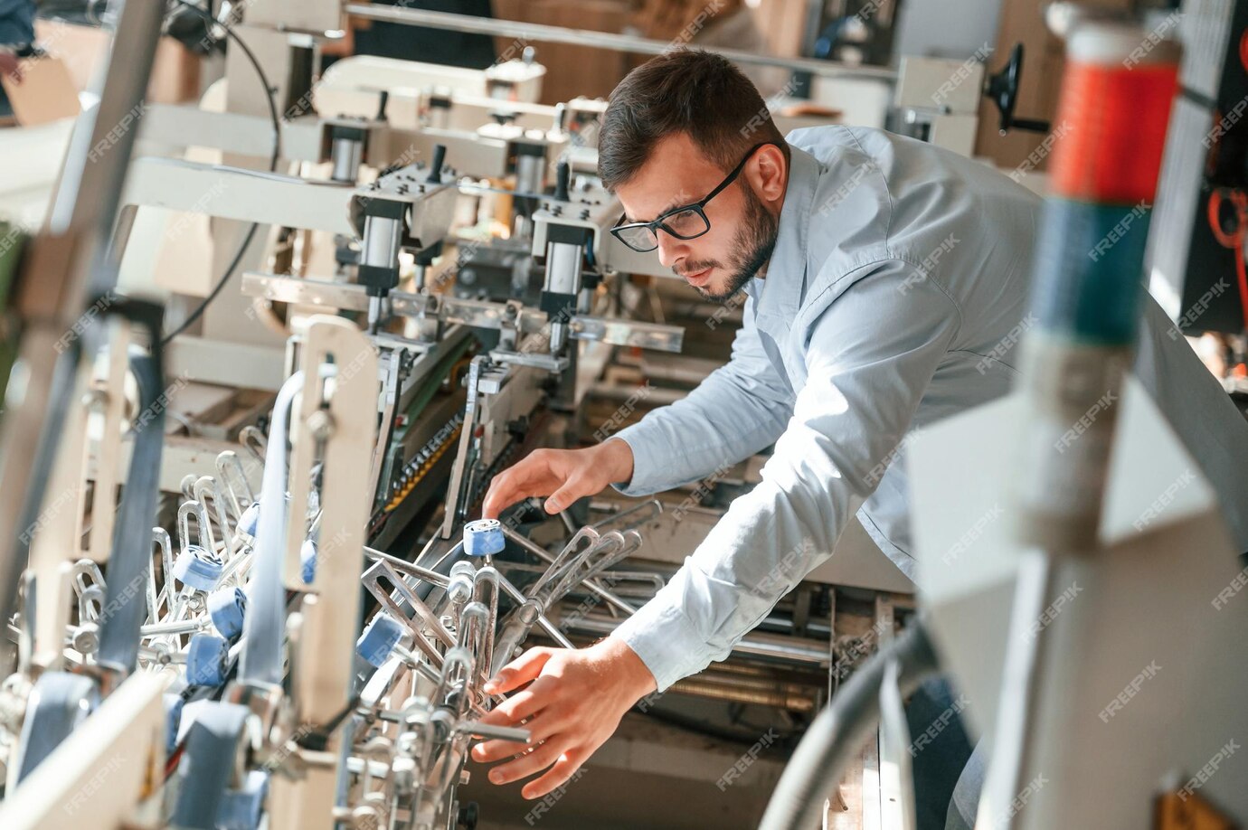 machine-operator-is-busy-by-setting-up-device-print-house-worker-white-clothes-is-indoors_146671-83433